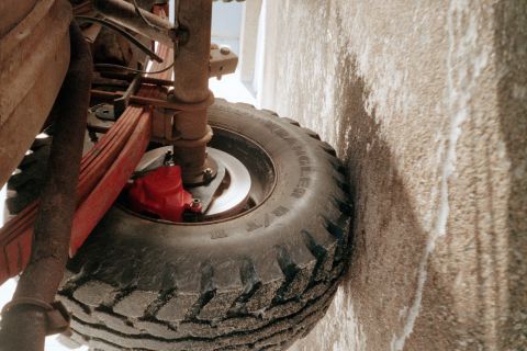 1979 Ford Bronco - Low-angle shot of a rear disc-brake conversion on a leaf-sprung axle, showing a bare vented rotor behind a Goodyear Wrangler R/T tire mount…