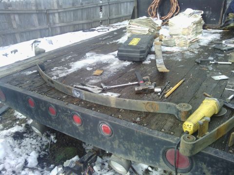 1995 GMC Safari - Tools and leaf springs are scattered on the wooden deck of a flatbed truck in the snow.