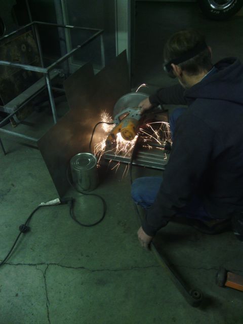 1995 GMC Safari - A person uses a grinder to cut metal, creating a shower of sparks in a workshop setting.