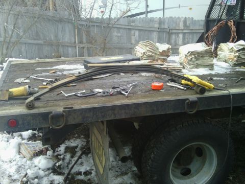 1995 GMC Safari - A leaf spring and various tools are laid out on the flatbed of a truck, with stacks of money visible in the background.