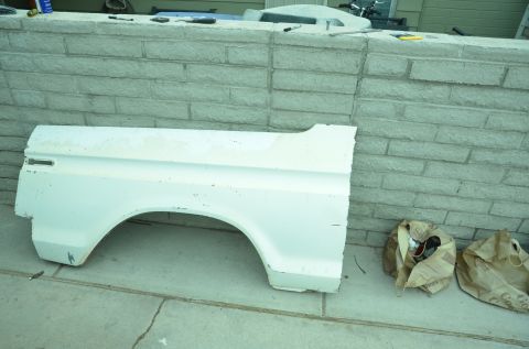 1979 Ford Bronco - A white fender with a wheel arch is shown, resting on a concrete surface.