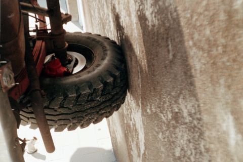 1979 Ford Bronco - Sideways-oriented shot of a Goodyear Wrangler all-terrain tire on a white steel wheel, mounted to a truck axle with a red-painted hub visib…