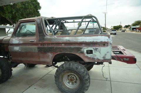 1979 Ford Bronco - Ford Bronco in body shop, showing roll cage and prep for paint. Tailgate is off.