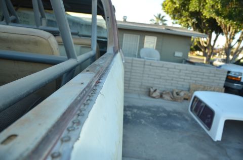 1979 Ford Bronco - Close-up view of a vehicle's interior roll cage and seats, with a camper shell and truck in the background.