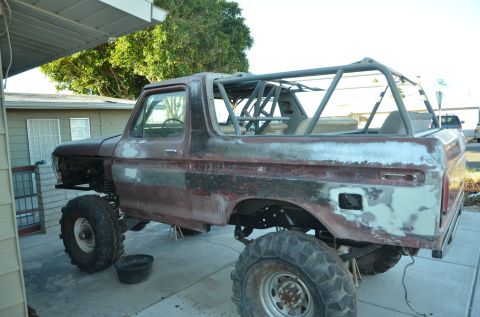 1979 Ford Bronco - This 1978 Ford Bronco is in a state of disrepair, with exposed metal and a prominent roll cage, indicating it's mid-restoration.