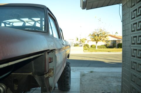 1979 Ford Bronco - The side of a weathered pickup truck is shown, with a residential street and house in the background.