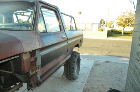 1979 Ford Bronco - This 1978 Ford Bronco shows significant rust and is missing its front fender, but features a roll cage and large off-road tires.