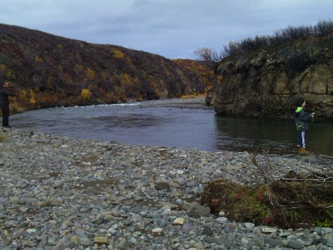 1990 Ford F-250 - Two individuals enjoy fishing by a river surrounded by rocky terrain and autumn-colored hills.