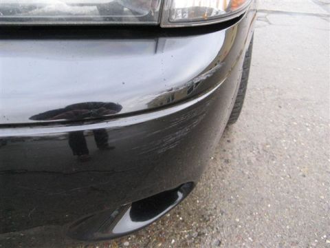 2003 Mercury Marauder - Close-up of a damaged black car bumper showing significant scratches and scuff marks.