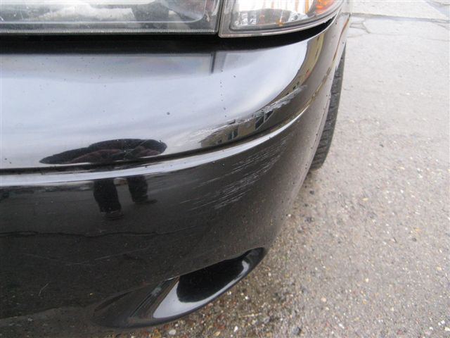 Scratched black car bumper with reflection of person