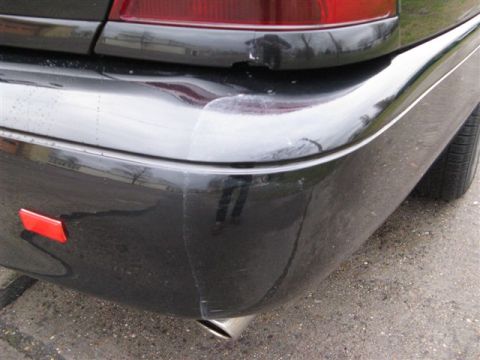 2003 Mercury Marauder - Close-up of the rear bumper and taillight of a black 2003 Mercury Marauder, showing some damage and the exhaust pipe.