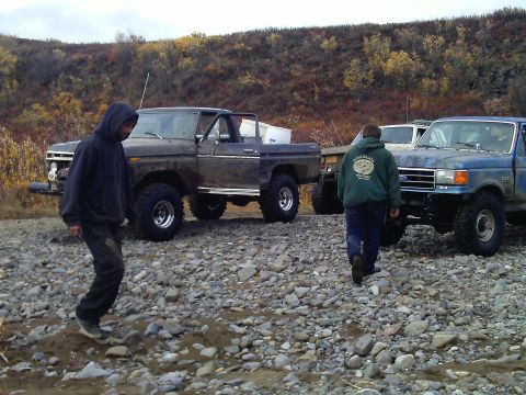 1990 Ford F-250 - Two pickup trucks are parked on a rocky surface in an outdoor setting with people present.