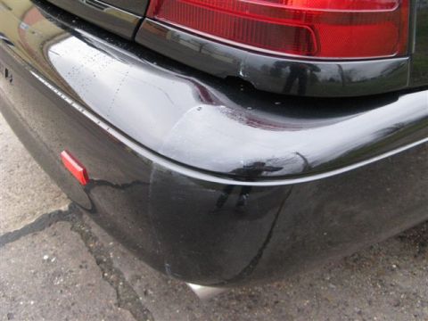 2003 Mercury Marauder - Close-up of a black car's rear bumper showing a red reflector and scuff marks.