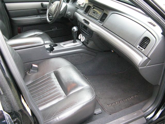 Black leather interior of a car with a floor mat that says MARAUDER