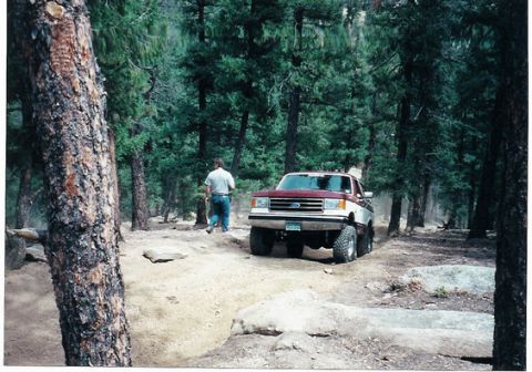 1996 Ford Bronco - Ford Bronco navigates a challenging off-road trail in a wooded area.