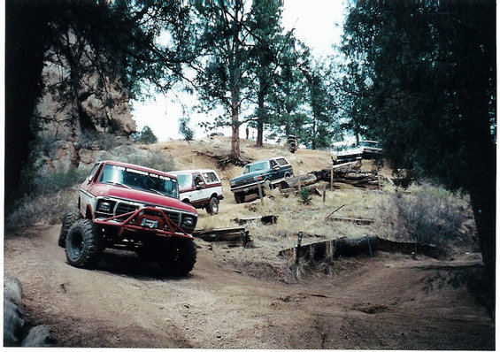 Red Ford Bronco with off-road modifications on a dirt trail