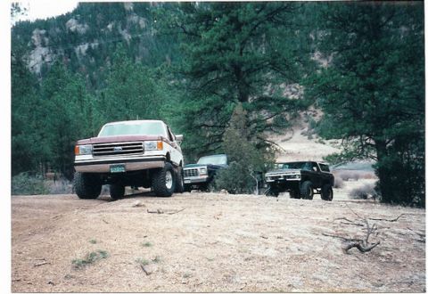 1996 Ford Bronco - Three SUVs are parked on a dirt road in a wooded, mountainous area.