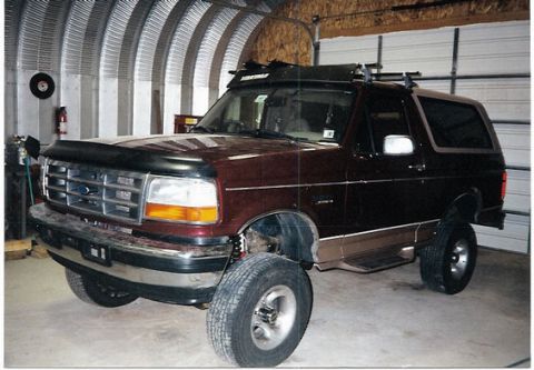 1996 Ford Bronco - This Ford Bronco is parked in a garage with a metal arched ceiling and a white garage door.