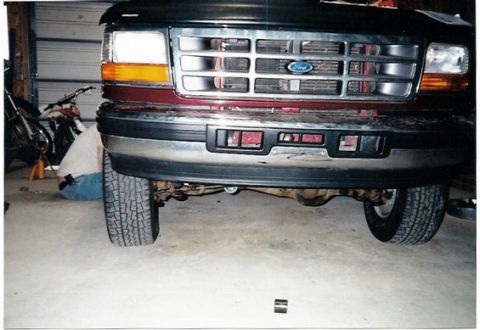 1996 Ford Bronco - Close-up of a Ford truck's front end, showing the grille, headlights, and tires.