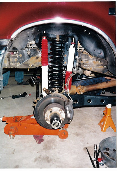 1996 Ford Bronco - Suspension components, including new shocks and springs, are visible during a lift installation on a red vehicle.