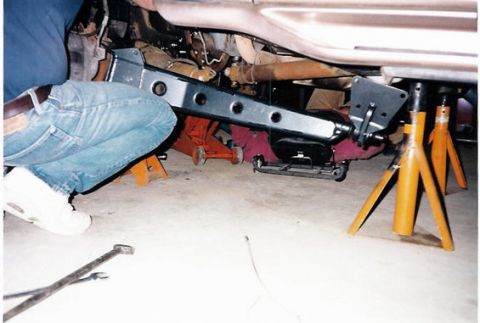 1996 Ford Bronco - Vehicle undercarriage with lift equipment and jack stands during maintenance or installation.