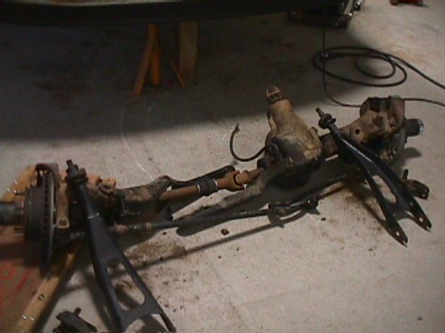 Front axle assembly with differential, brake rotor, and suspension components on a concrete floor