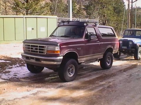 1996 Ford Bronco - Maroon 1996 Ford Bronco with roof rack, parked next to a blue Jeep CJ on a dirt road.