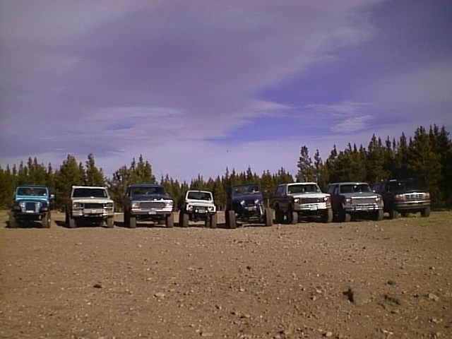 Line of SUVs and trucks parked on dirt lot, 1996 Ford Bronco among them