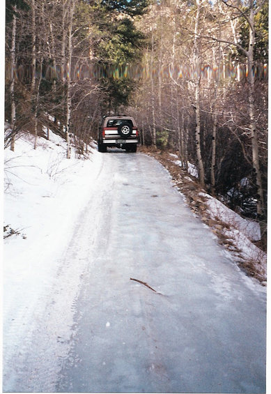 1996 Ford Bronco - A 1996 Ford Bronco navigates an icy road through a snowy forest, its spare tire mounted on the rear.