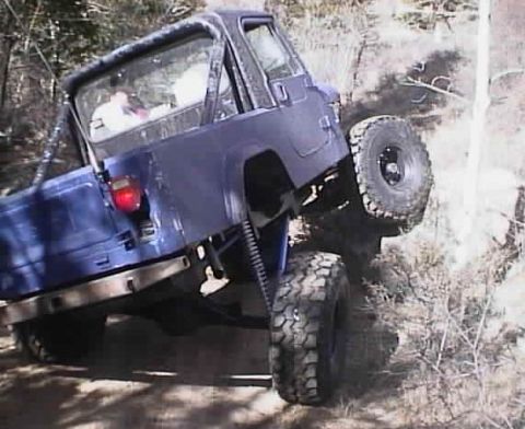 1996 Ford Bronco - A blue Jeep Wrangler is shown navigating a steep, rocky incline off-road.