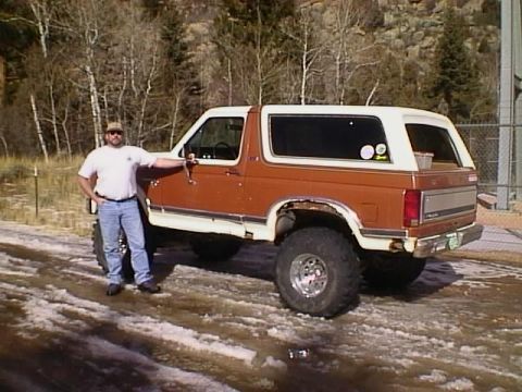 1996 Ford Bronco - A man poses with a lifted, two-tone brown and white Ford Bronco, likely from the early 1980s.
