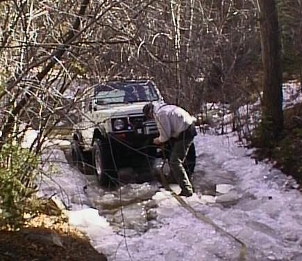 1996 Ford Bronco - A person attempts to free a Suzuki Samurai stuck in an icy, wooded area.