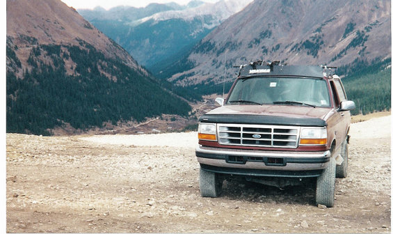 1996 Ford Bronco parked on a dirt road with mountains in the background