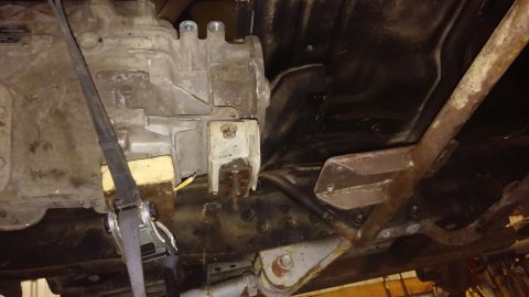 1995 Ford Bronco - Underside view of vehicle transmission and frame components, with a ratchet strap and block visible.