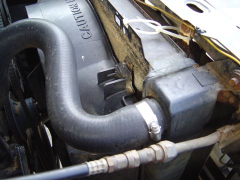 1986 Ford Bronco - Close-up view of a radiator fan shroud with a "CAUTION" warning and a hose connected.