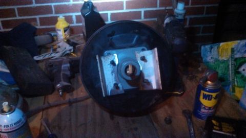 1979 Ford Bronco - Brake booster assembly on a workbench with various automotive parts and tools.