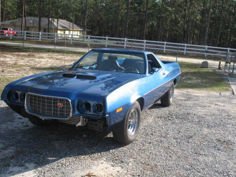 1972 Ford Ranchero - A blue 1972 Ford Ranchero is parked outside a house with trees in the background.