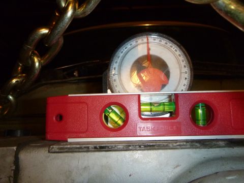 1953 Plymouth Belvedere - A red level and inclinometer are used to measure angles, with heavy chains visible overhead.