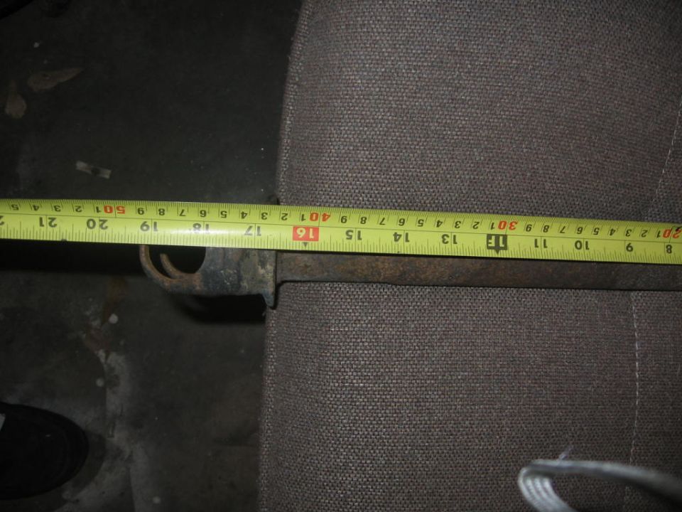 Metal rod with yellow tape measure showing 16 to 21 inches, resting on gray fabric