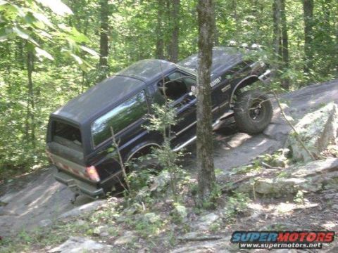 1988 Ford Bronco - A black 1988 Ford Bronco navigates a rocky, wooded path during an off-road excursion.