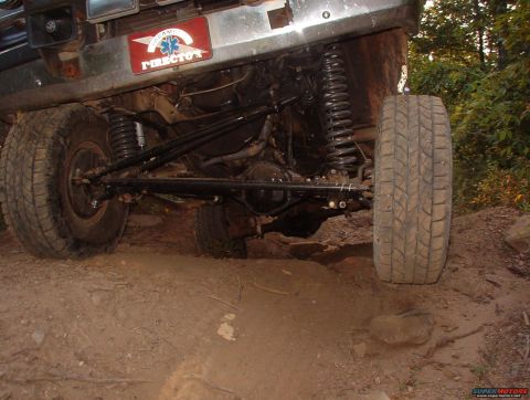 1988 Ford Bronco - The underside of an off-road vehicle is shown navigating rough terrain, with visible suspension and drivetrain components.
