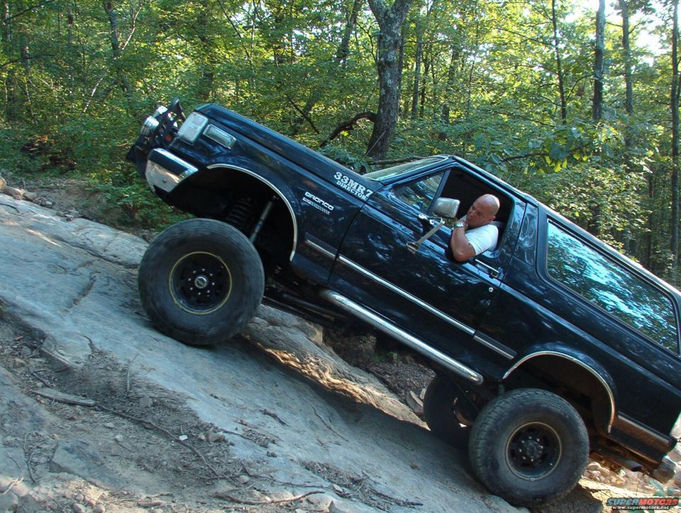 Black Ford Bronco climbing a rocky hill with a driver inside