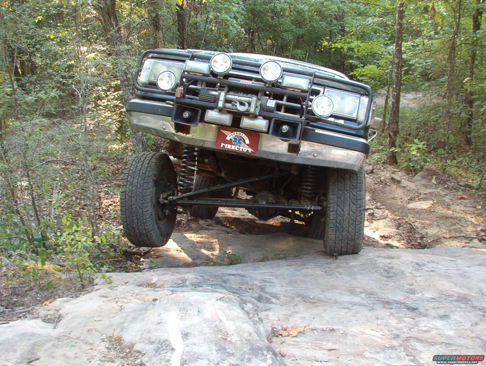 Off-road vehicle with one wheel off the ground, front bull bar, and auxiliary lights