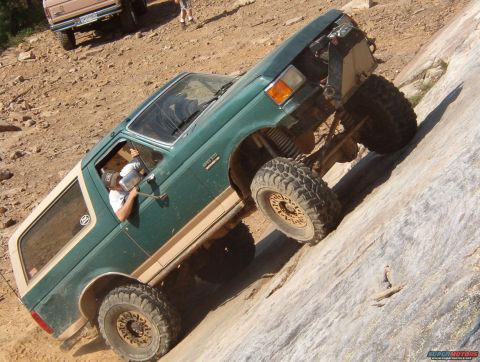 1988 Ford Bronco - A green Ford Bronco navigates a steep rocky incline, with another vehicle visible in the background.