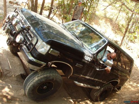 1988 Ford Bronco - This black SUV is shown tackling a challenging off-road course with steep inclines and obstacles.