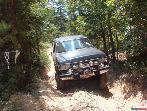 1988 Ford Bronco - This black 1988 Ford Bronco navigates a challenging dirt path through a wooded area.