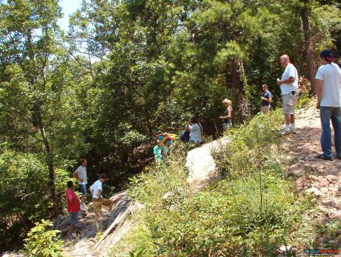 1988 Ford Bronco - A group of people are gathered on a wooded hillside next to a dirt path.