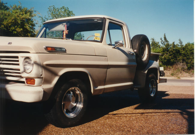 Left front three-quarter view of white classic Ford stepside pickup on gravel