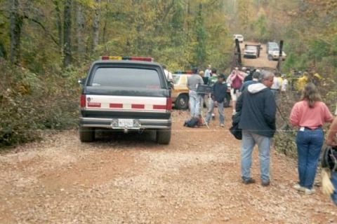 1988 Ford Bronco - The rear of a black 1988 Ford Bronco with red and white reflective stripes on the tailgate is parked on a gravel road in a wooded area. Sev…