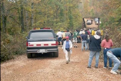 1988 Ford Bronco - A black Ford Bronco with red and yellow emergency lights on the roof is parked on a gravel road in a wooded area. A crowd of people are gat…